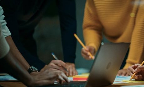 Three people in a business meeting looking at a laptop