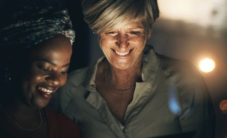 Two people smiling looking at a tablet